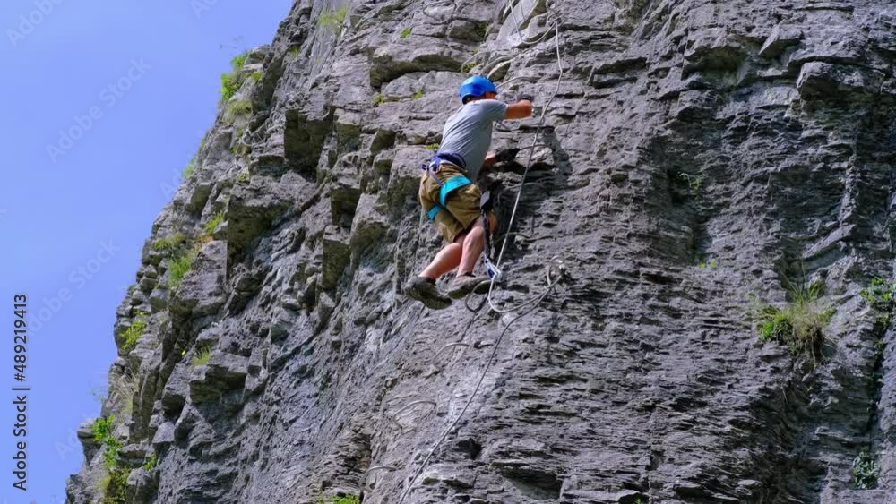 man in body harnesses feature life-safety, attaches hooks to iron brackets, climbs rock, active lifestyle of people, mountaineering, via ferrata in mountains of alps, life insurance in extreme sports man in body harnesses feature life-safety, attaches hooks to iron brackets, climbs rock, active lifestyle of people, mountaineering, via ferrata in mountains of alps, life insurance in extreme sports