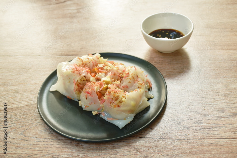 roll steamed large rice noodles stuffed slice fried tofu and chop pork dressing dry shrimp dipping with black sweet soy sauce on plate