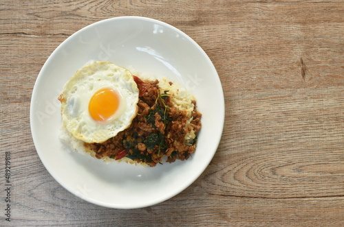 stir-fried spicy chop pork with basil leaf topping egg on rice in plate