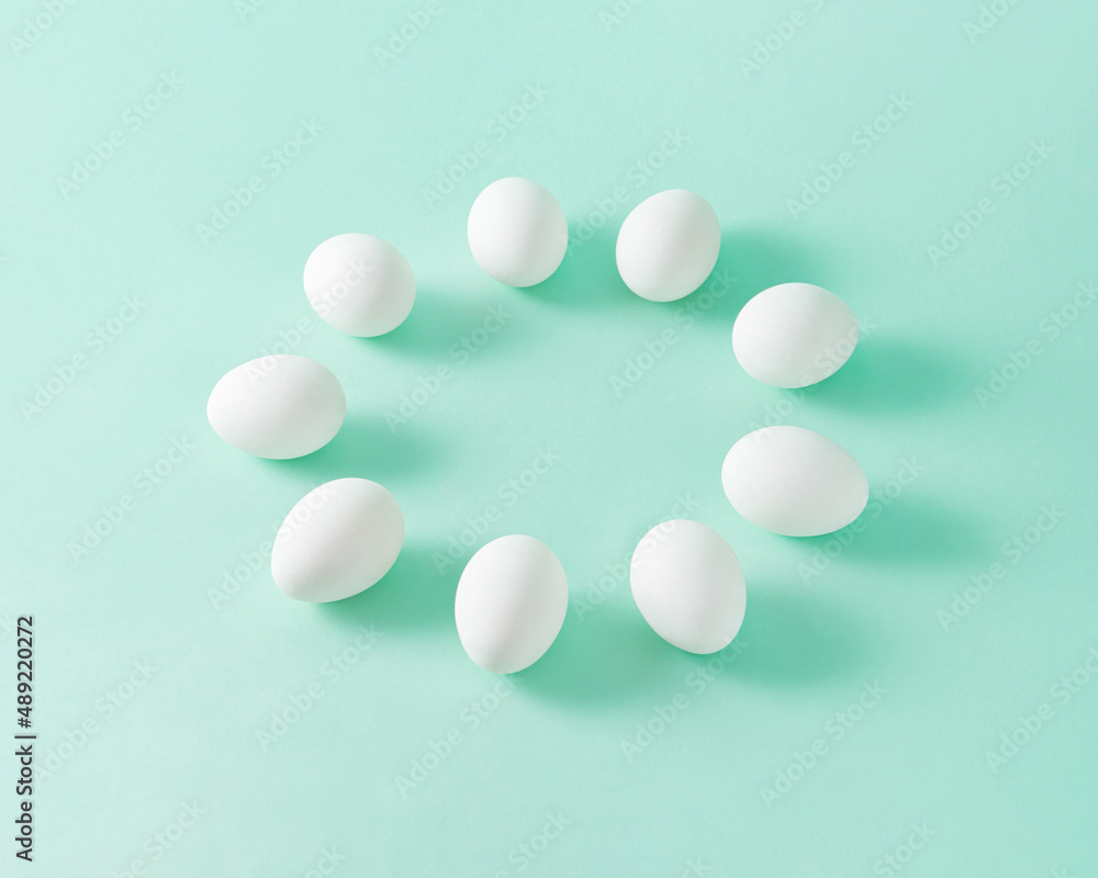 Minimal isometric composition with white eggs lined up in a circle on pastel olive green background with copy space. Minimal isometric composition with white eggs lined up in a circle on pastel olive green background with copy space.