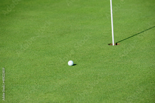 Hole cup and golf ball on the green of a golf course.