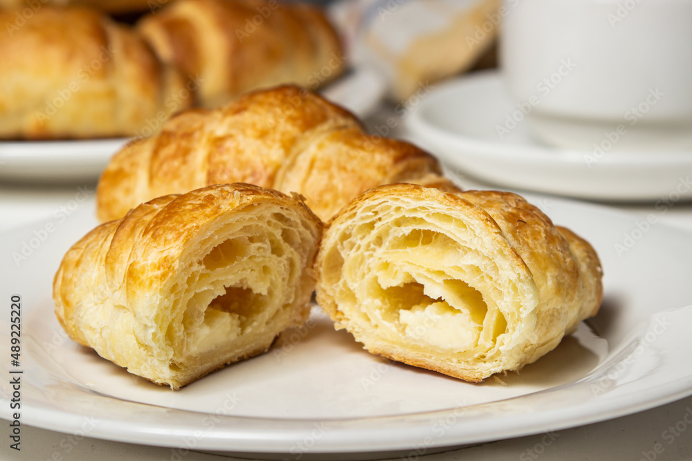 Croissant cut in half on a white plate. Tasty breakfast. Traditional pastries.