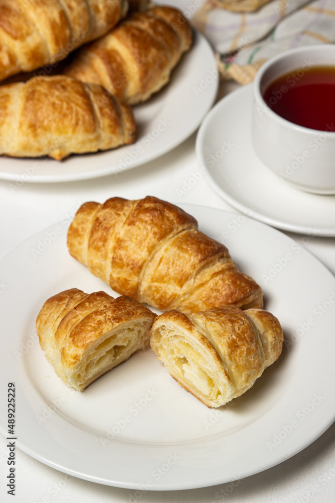Croissant cut in half on a white plate. Tasty breakfast. Traditional pastries.