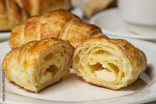 Croissant cut in half on a white plate. Tasty breakfast. Traditional pastries. © Ruzanna