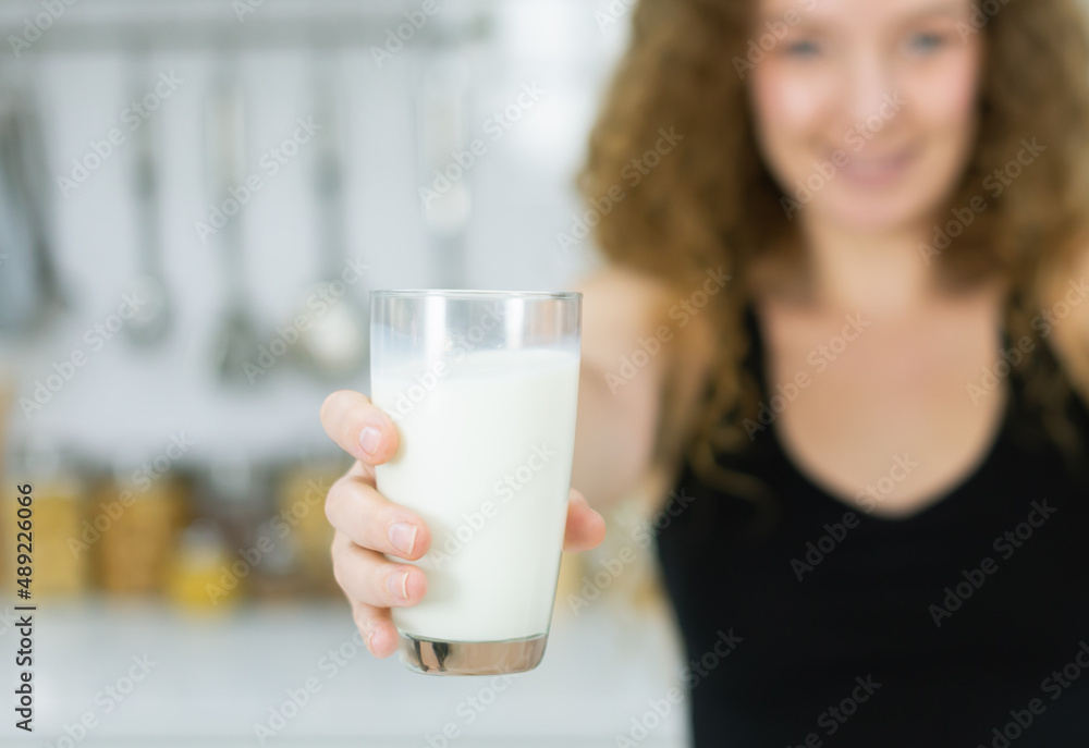 milk glass in hand of smart woman while looking at camera in kitchen with copy space. beautiful caucasian woman cooking healthy diet fruit or vegetable in kitchen. milk glass in hand of smart woman while looking at camera in kitchen with copy space. beautiful caucasian woman cooking healthy diet fruit or vegetable in kitchen.