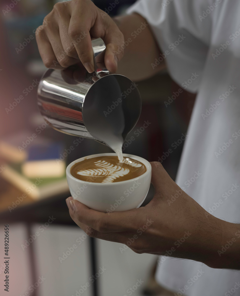 Coffee cup was holding by human hand,pouring milk from stainless jar for making latte art, Coffee cup was holding by human hand,pouring milk from stainless jar for making latte art,