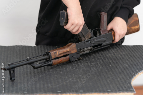 A person with a gun. A girl learns to assemble and disassemble a Kalashnikov assault rifle