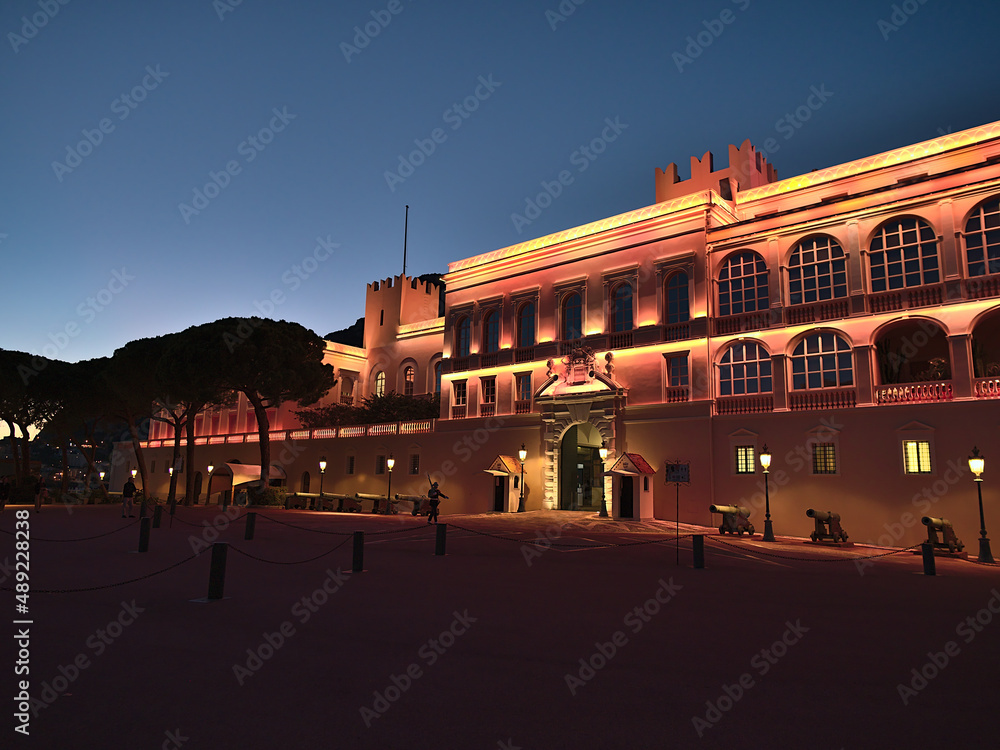 Beautiful night view of Genoese Prince's Palace of Monaco after sunset at the French Riviera with illuminated facade, cannons and patroling guard.