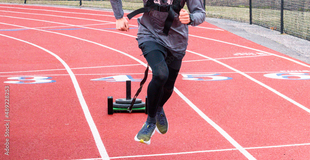 Front view of a runner pulling a sled with weights on a track