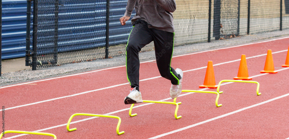 Fototapeta premium Runner running over six inch hurdles on a track