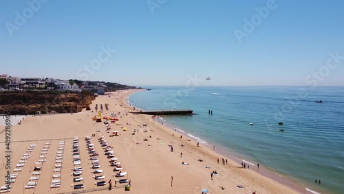 Praia dos Alamaes Beach at Albufeira, Algarve, Portugal - Aerial drone View of the Sandy Beach with Tourists and Parasailing Boat photo