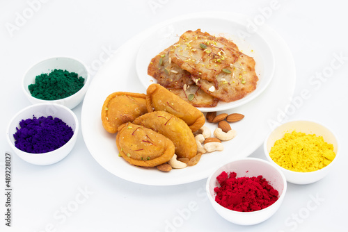 Exotic Indian Mawa Gujia And Malpua Soaked Or Dunken In Sugar Syrup Served With Colorful Red, Green, Blue Yellow Herbal Gulal Holi Color Powder. Isolated On White Background With Copy Space