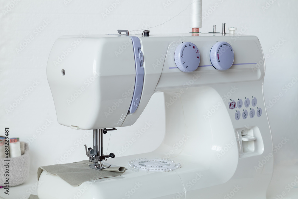 White modern sewing machine on a white table. Tailor's workplace.