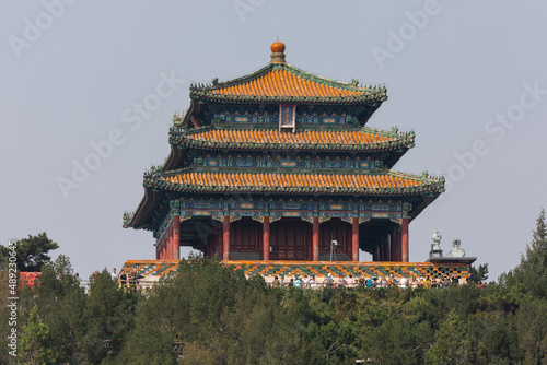 Eine dreistöckige traditionell chinesische Pagode, geziert mit Säulen einem chinesischen dreistufige Dach sowie einem roten Säulengang, thront auf einem Hügel über der Stadt Peking photo