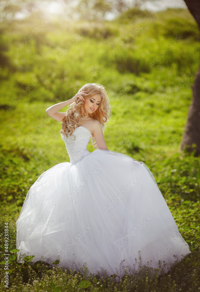 A beautiful blonde bride with a cool make-up in a wedding dress holds a bridal bouquet against the backdrop of a beautiful, green nature. Husband and wife, happy together, just married, newlyweds. A beautiful blonde bride with a cool make-up in a wedding dress holds a bridal bouquet against the backdrop of a beautiful, green nature. Husband and wife, happy together, just married, newlyweds.