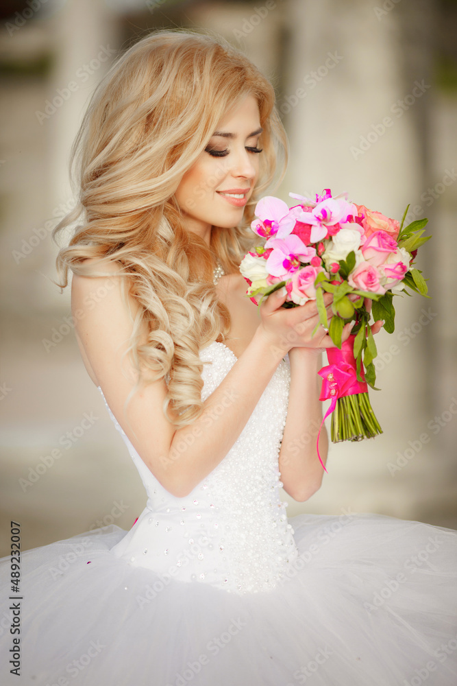 A beautiful blonde bride with a cool make-up in a wedding dress holds a bridal bouquet against the backdrop of a beautiful, green nature. Husband and wife, happy together, just married, newlyweds. A beautiful blonde bride with a cool make-up in a wedding dress holds a bridal bouquet against the backdrop of a beautiful, green nature. Husband and wife, happy together, just married, newlyweds.