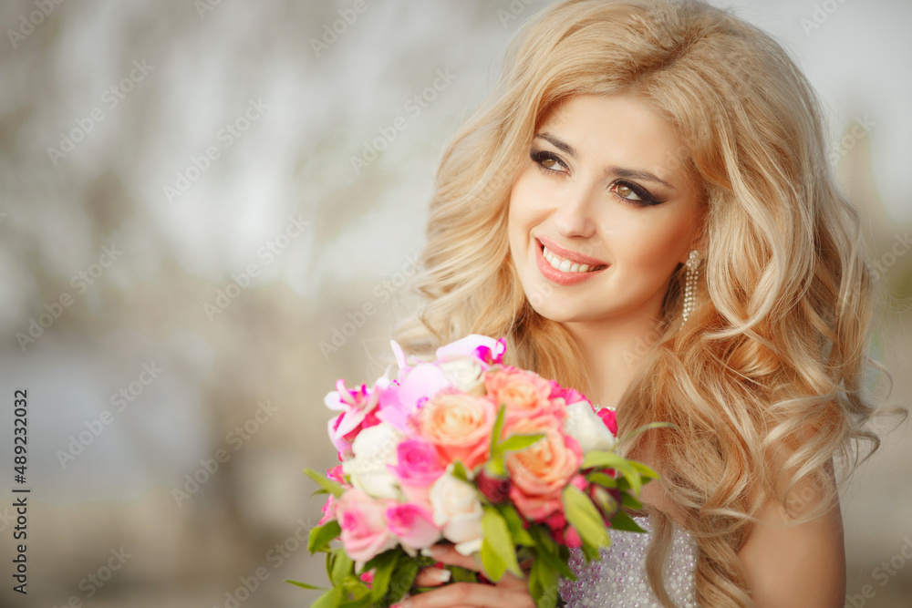 A beautiful blonde bride with a cool make-up in a wedding dress holds a bridal bouquet against the backdrop of a beautiful, green nature. Husband and wife, happy together, just married, newlyweds.