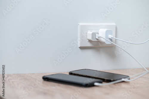 smart phone charger plugged on wooden with plugged at home.