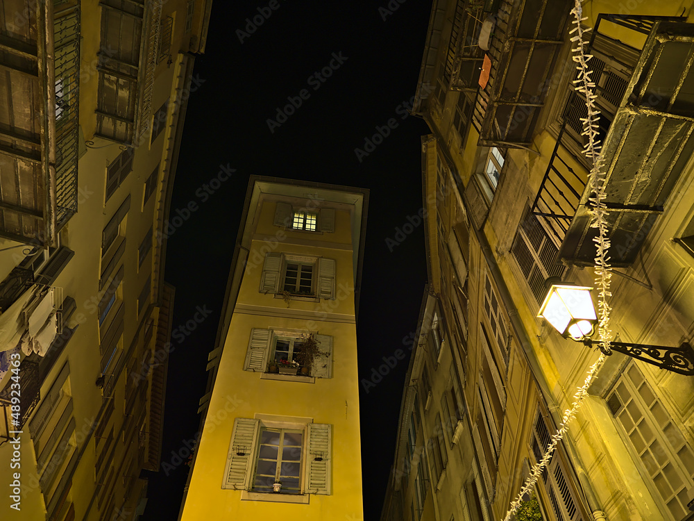 Stunning low angle view by night of very narrow old building in the historic center of Nice, France at the French Riviera with illuminated facade. Stunning low angle view by night of very narrow old building in the historic center of Nice, France at the French Riviera with illuminated facade.