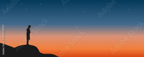 Traveler standing on top of a mountain with sunset background. Exploration, hiking, adventure tourism, and travel.
