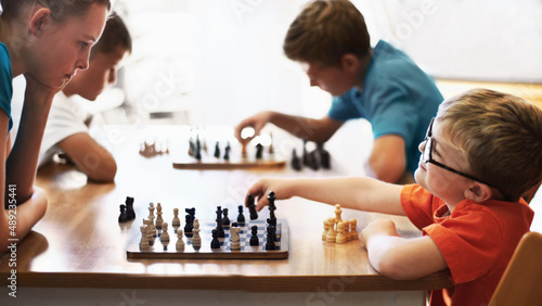 Chess whiz. Young boy wearing spectacles and playing chess with an older child. photo