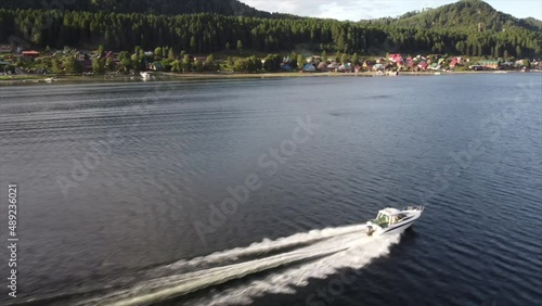 the boat goes through the water at high speed among the mountains of houses and forests. Drone video.