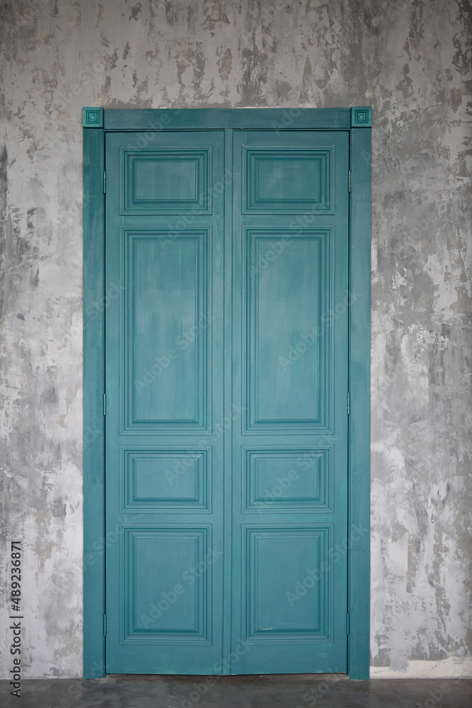 An old blue door in a concrete wall.