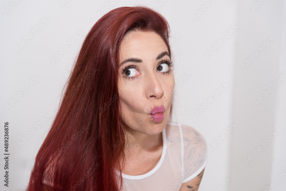 red-haired girl, throwing a kiss, looking straight ahead, with neutral background. red-haired girl, throwing a kiss, looking straight ahead, with neutral background.