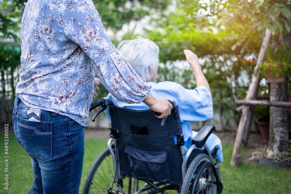 Obraz premium Caregiver help and care Asian senior or elderly old lady woman patient sitting on wheelchair at park in nursing hospital ward, healthy strong medical concept.