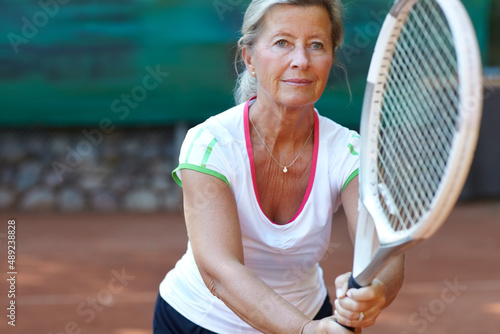 Dedicated tennis player. Senior woman preparing to return a serve during a game of tennis. photo