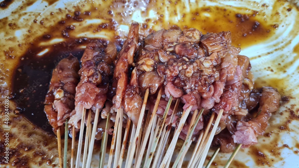 Satay or Sate Kambing, meat satay served with slice red onion, ​​chili, ​​tomatoes with soy sauce on plate. Selective focus image.