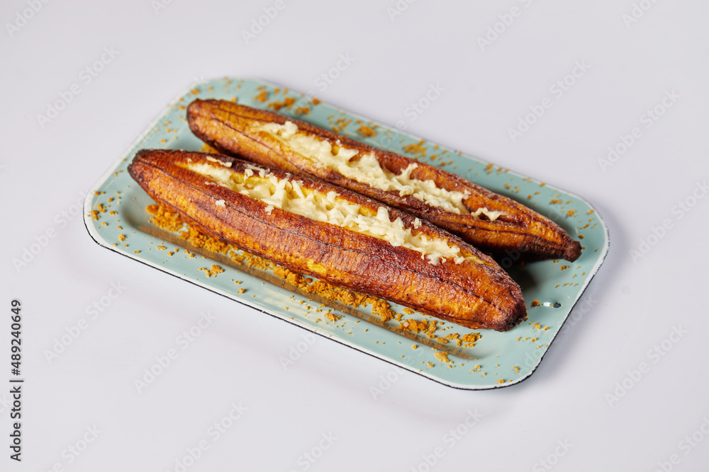 Ecuadorian maduro con queso consists of baked ripe plantains stuffed with cheese. It’s on a white background. Ecuadorian maduro con queso consists of baked ripe plantains stuffed with cheese. It’s on a white background.
