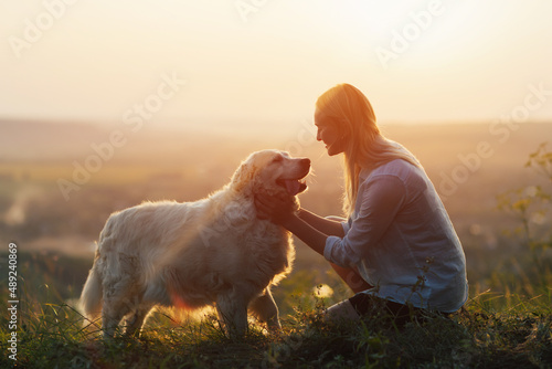 
Special and sincere moment as a girl is lovingly hugging her Golden retriever against the sunsetting sky
