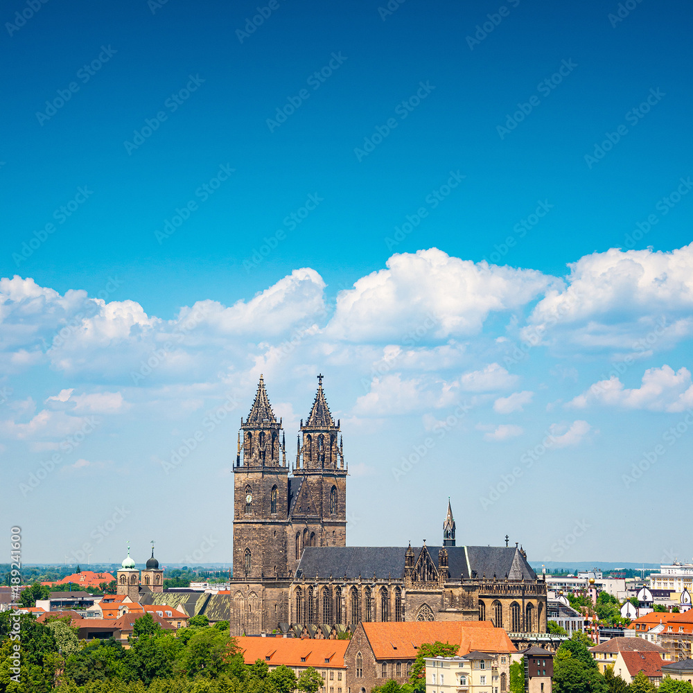 Fototapeta premium Cover page with Magdeburg historical downtown, Elbe river, city park and the ancient medieval cathedral in Spring colors at blue cloudy sky and sunny day, Magdeburg, Germany.