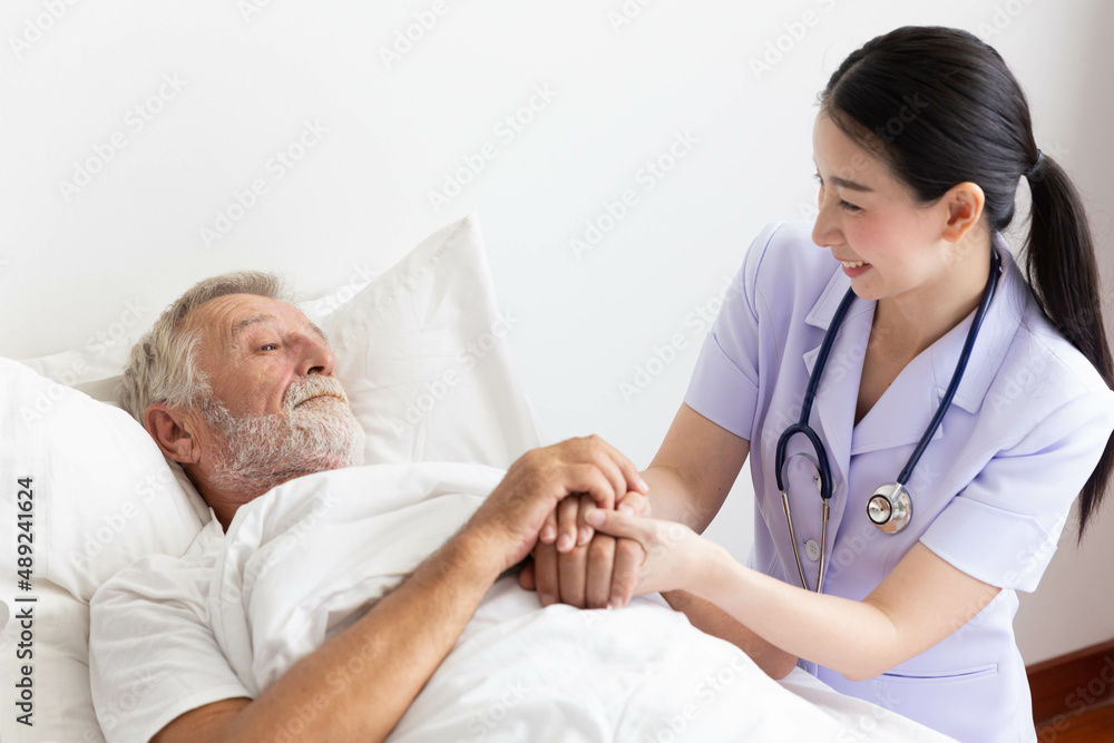 Nurse cares for elderly man lying in bed Nurse cares for elderly man lying in bed