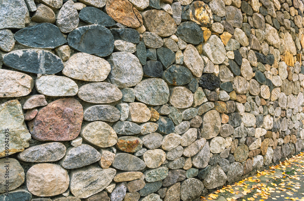 Background of stones. A wall of multicolored stones. The masonry is made of untreated stones. A wall of large stones. Background of stones. A wall of multicolored stones. The masonry is made of untreated stones. A wall of large stones.
