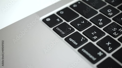 Hand pressing control key on modern laptop keyboard close-up slow motion 