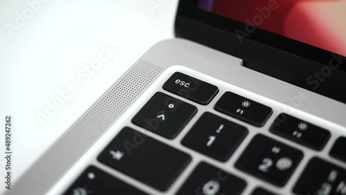 Hand pressing escape key on modern laptop keyboard close-up slow motion video