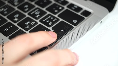 Hand pressing enter key several times on modern laptop keyboard close-up slow motion video