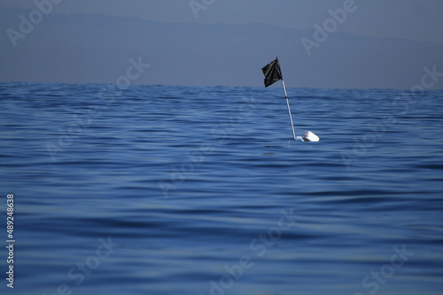 Bandiera nera realizzata con un sacco della spazzatura, in mezzo al mare, per indicare la posizione di una boa e palamito sott'acqua photo