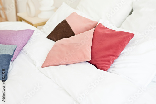 Colorful pillows made of ecological materials on a white sheet on the bed in the hotel.