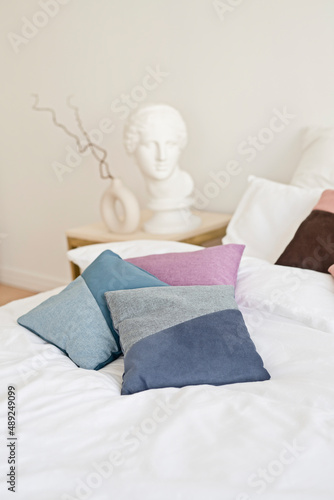 Colorful pillows made of ecological materials on a white sheet on the bed in the hotel.