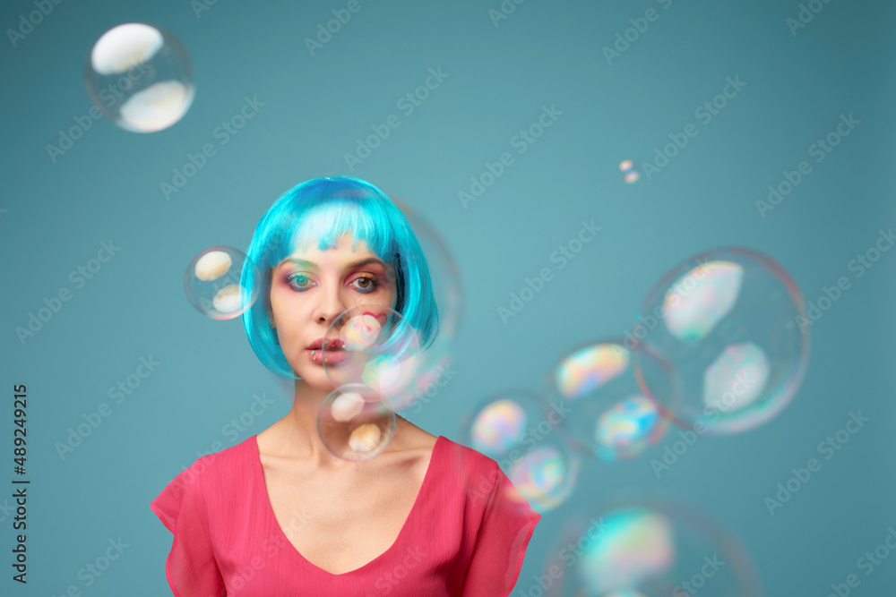 Beautiful young woman with blue wig and bright make-up in soap bubbles. Fashion model girl with creative color makeup. Women doll concept. Beautiful young woman with blue wig and bright make-up in soap bubbles. Fashion model girl with creative color makeup. Women doll concept.