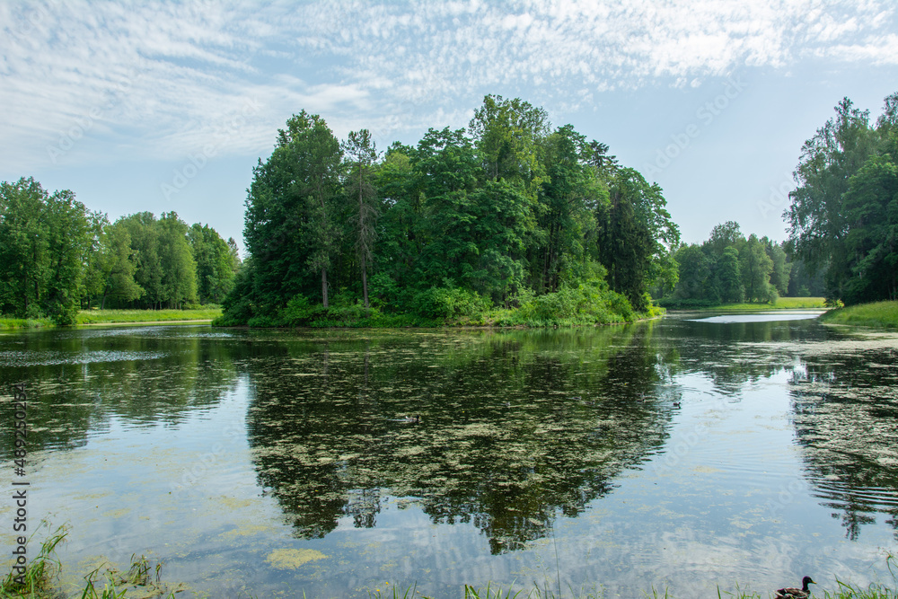 Fototapeta premium The view of the Charlotte Lieven island mirroring in the lake in the middle of the Pink Pavilion Pond in Pavlovsk Park, St Petersburg, Russia