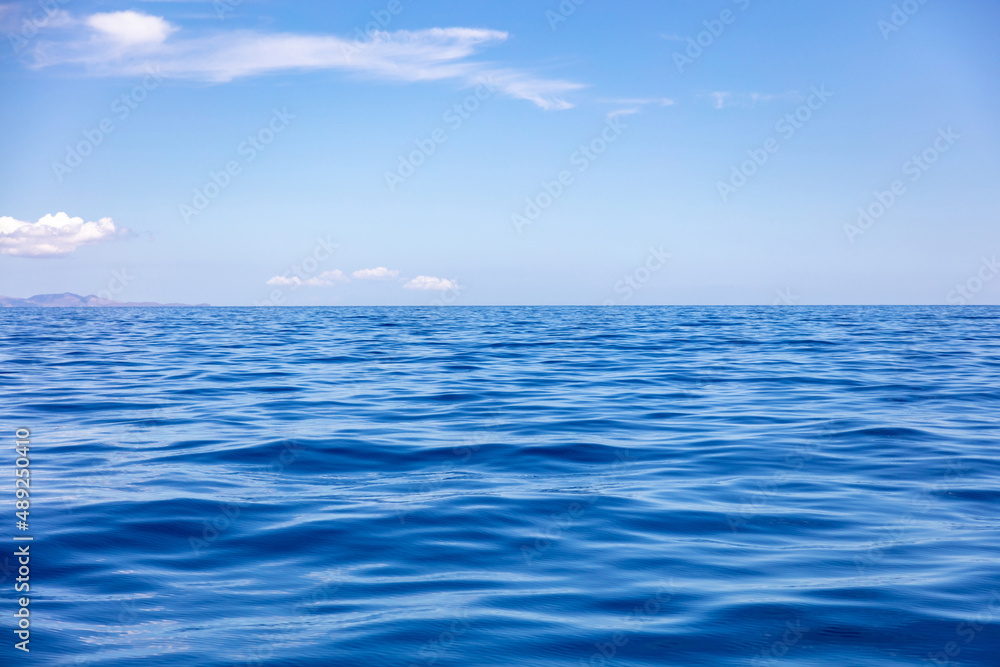 Fototapeta premium Ocean sea water surface deep blue, calm with ripple, small cloud on blue sky background,