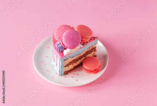 piece of cake with pink and blue decor on white plate on pink background