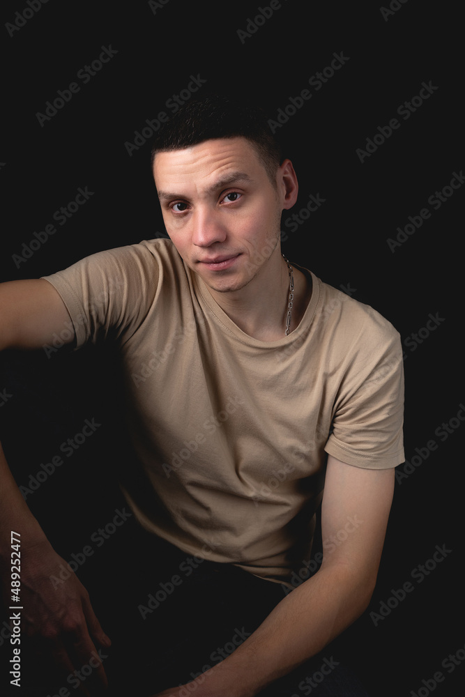 Handsome guy posing in studio on isolated black background. Studio portrait with one light source.