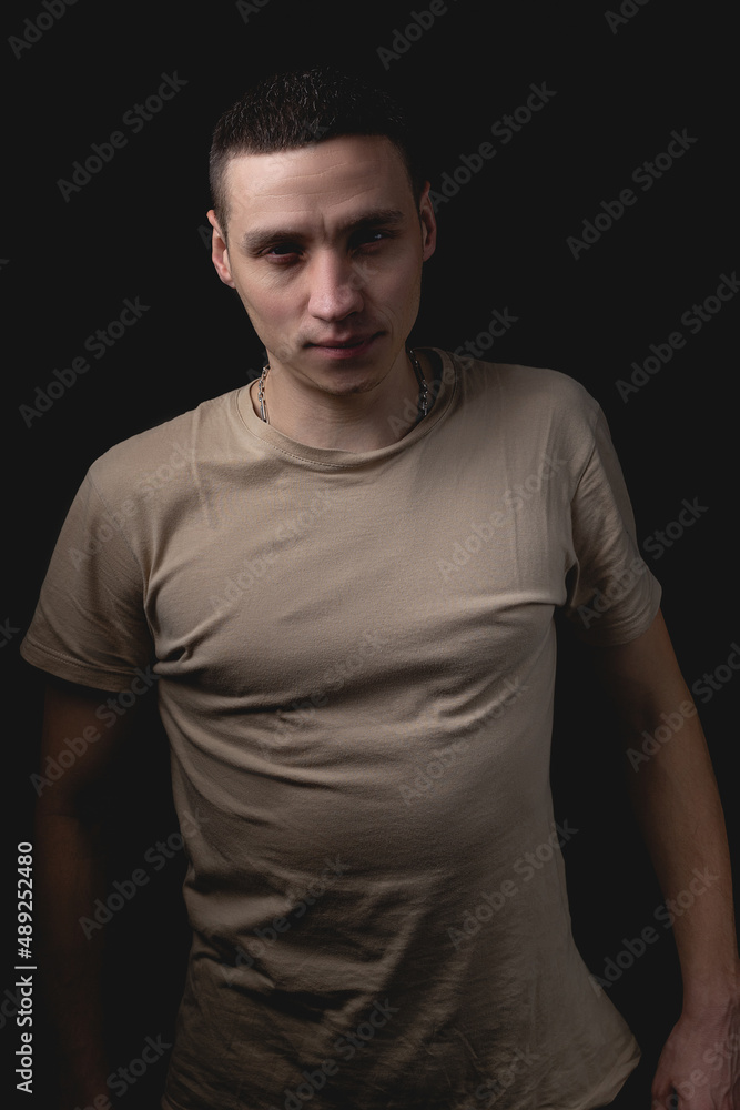 Fototapeta premium Handsome guy posing in studio on isolated black background. Studio portrait with one light source.