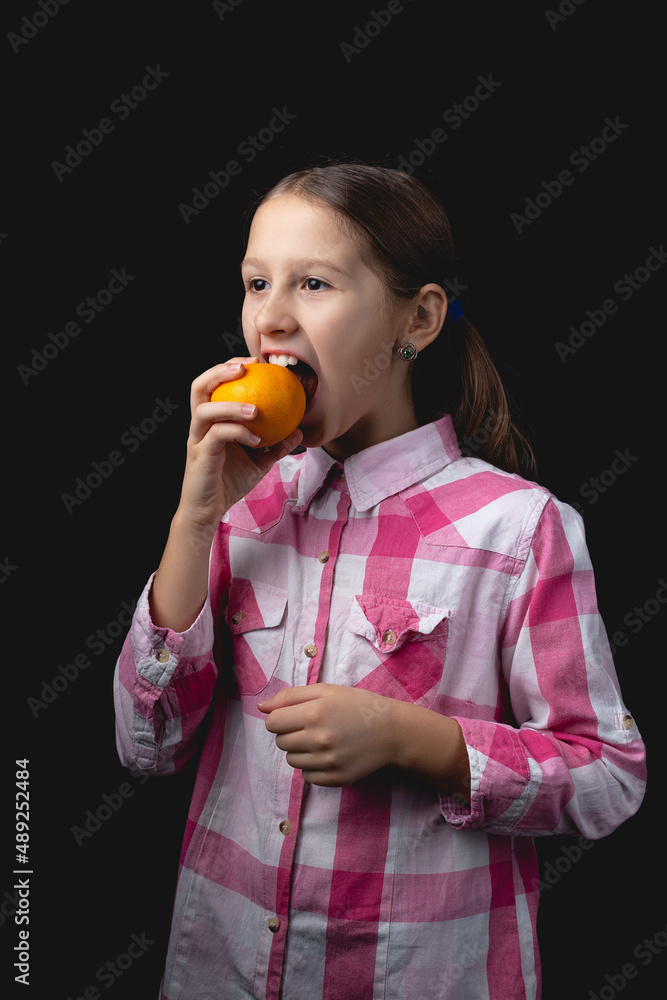 Little cute girl with tangerine posing in the studio on a black background. Little cute girl with tangerine posing in the studio on a black background.