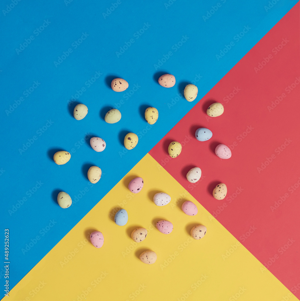 Easter eggs lay down in a circle on a multicolored geometric background. Square flat lay composition with copy space, minimal Easter celebration concept Easter eggs lay down in a circle on a multicolored geometric background. Square flat lay composition with copy space, minimal Easter celebration concept